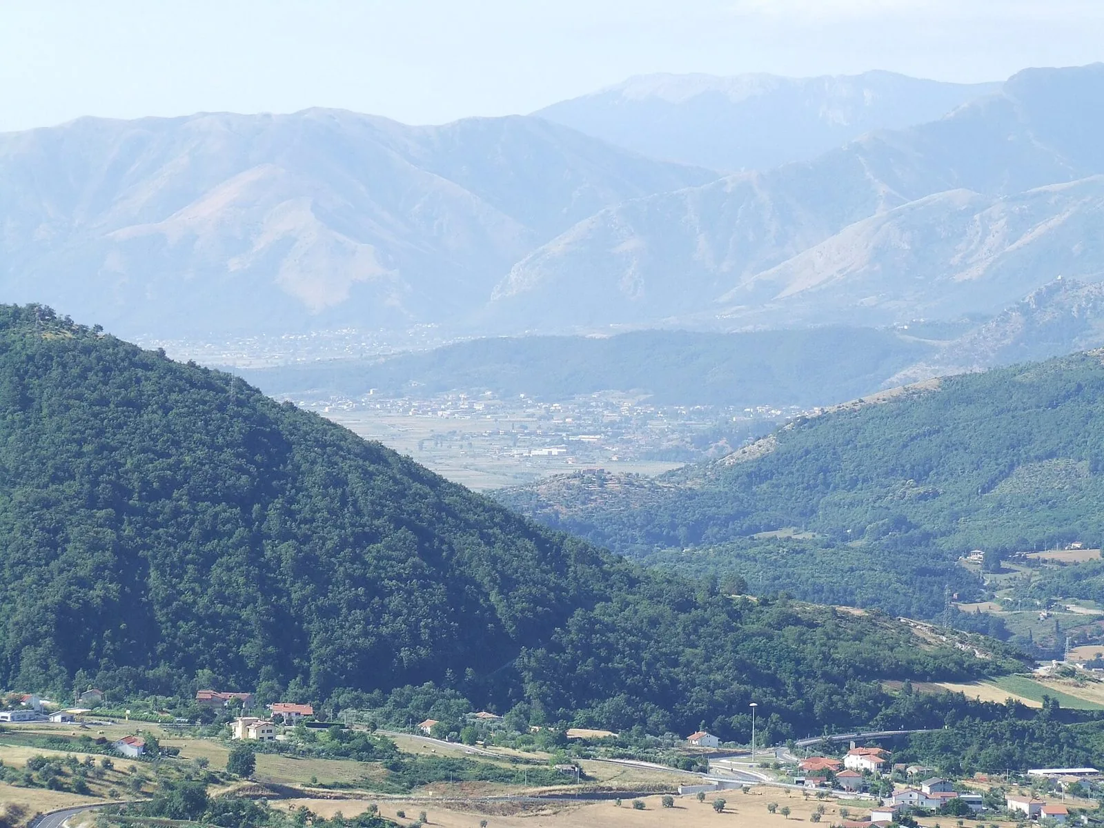 Colline boscose e piana del Vallo di Diano con i monti Alburni sullo sfondo, vista da Caggiano